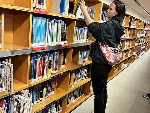 Eine Kollegin erforscht die Regale der Bibliothek.