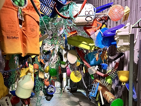 Fischernetze, Rettungswesten, Bojen und andere Fundsachen ergeben ein buntes Kunstwerk.